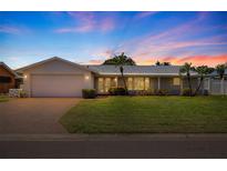 Charming single-story home with well-manicured lawn, brick driveway, and attached two-car garage at sunset at 4433 38Th S Way, St Petersburg, FL 33711