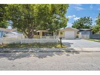 Charming one-story home with a well-maintained lawn, picket fence, and mature shade tree in a residential neighborhood at 8733 Goshen Ln, Port Richey, FL 34668