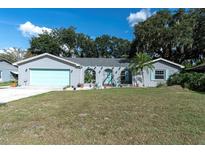 Charming single-story home with a well-manicured lawn, blue trim, and an attached garage at 10907 Kewanee Dr, Temple Terrace, FL 33617