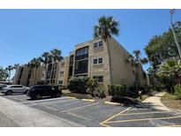Low angle view of condo building with palms and reserved parking spaces on a sunny day at 11485 Oakhurst Rd # 319, Largo, FL 33774