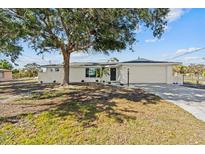A charming single-story home features a large front yard with a well-manicured lawn and mature trees at 1499 Janet Pl, Englewood, FL 34223