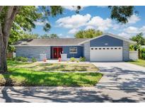 Charming home featuring a two-car garage, well-manicured lawn, and a welcoming facade at 2671 Clubhouse N Dr, Clearwater, FL 33761
