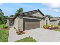 Well-maintained exterior with a concrete driveway, lovely landscaping, and a two car garage at 2821 Lytton Hall Dr, Zephyrhills, FL 33540