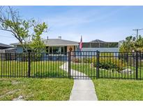Charming, blue one story house features a tidy front yard, and black metal fence at 4013 W Waterman Ave, Tampa, FL 33609