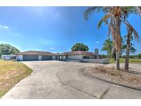 Sprawling ranch home boasts a circular driveway, neutral paint, and a spacious three-car garage at 6709 W Knights Griffin Rd, Plant City, FL 33565