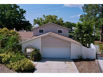 Two-story home features an attached garage, landscaped yard, and neutral color scheme on a sunny day at 7307 Summerbridge Dr, Tampa, FL 33634