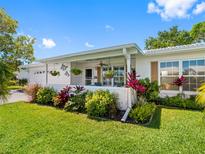 Charming single-story home with a well-manicured lawn and colorful, tropical landscaping in the front yard at 9110 34 N Way, Pinellas Park, FL 33782