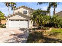 Charming home featuring a two-car garage, lush landscaping, and a brick paver driveway at 11503 Whispering Hollow Dr, Tampa, FL 33635