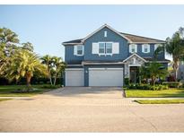 Charming two-story blue home featuring a three-car garage and well-manicured lawn at 12026 Medley Ter, Lakewood Ranch, FL 34211
