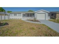 Charming single-story home with a screened-in porch and an attached garage with driveway at 1264 Chelsea Ln, Holiday, FL 34691
