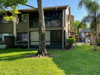 Condominium exterior featuring well-maintained lawn and patio seating at 12920 Wedgewood Way # A, Hudson, FL 34667