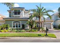 Charming two-story home featuring a well-manicured lawn, tropical landscaping, and a gray stucco exterior at 16629 Sedona De Avila, Tampa, FL 33613
