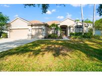 Charming single-story home featuring a well-maintained lawn, a two-car garage, and a welcoming entrance at 18310 Bankston Pl, Tampa, FL 33647