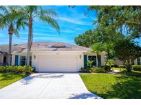 Charming single-story home with a two-car garage, neat landscaping, and palm trees in a sunny setting at 2333 Brookfield Greens Cir, Sun City Center, FL 33573