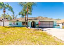 Charming single-story home featuring a light-blue exterior, arched entryway, and well-maintained front lawn at 2435 Comerwood Dr, Spring Hill, FL 34609