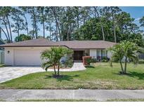 Charming single-story home featuring a two-car garage, well-manicured lawn, and tropical landscaping at 2486 Indian E Trl, Palm Harbor, FL 34683