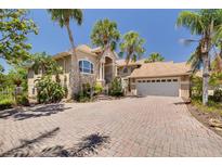 Beautiful home exterior with a brick driveway, a two-car garage, stone accents, and tropical landscaping at 2613 59Th S St, Gulfport, FL 33707