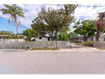 View of the property from the street, featuring an overgrown front yard and a distressed house at 4111 W Marietta St, Tampa, FL 33616