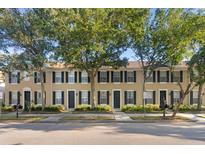 Charming townhomes featuring black shutters, well-manicured landscaping, and mature trees at 9534 W Park Village Dr, Tampa, FL 33626
