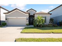 Charming single-story home with a well-manicured lawn and a two-car garage on a sunny day at 10303 Malvasia Ave, Riverview, FL 33578