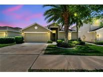 Inviting home featuring a lush lawn, mature trees, and a two-car garage at 11506 Mansfield Point Dr, Riverview, FL 33569