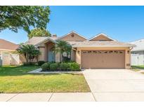 Charming single Gathering home featuring manicured lawn, mature trees, and two car garage at 1285 Salt Lake Dr, Tarpon Springs, FL 34689