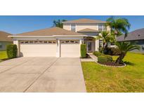 Inviting home featuring a two-car garage, arched entry, and mature landscaping at 2256 Pantucket Dr, Wesley Chapel, FL 33543