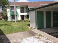 Condominium building with green storage unit and green trim, surrounded by lush lawn and trees at 2555 Royal Pines Cir # A, Clearwater, FL 33763