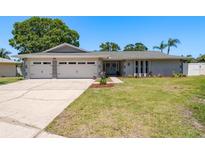 Charming single-story home with a two-car garage, manicured lawn, and light gray paint at 3241 Brushwood Ct, Clearwater, FL 33761