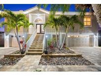 Two-story home with mature landscaping, a dual garage and a prominent elevated entrance at twilight at 3505 Seaway Dr, New Port Richey, FL 34652