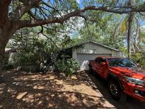 Modest single Gathering home with mature shade trees and an orange pickup truck in the driveway at 5517 Pentail Cir, Tampa, FL 33625