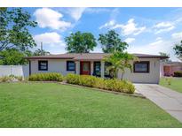 Charming single-story home featuring a well-maintained lawn, mature trees, and inviting curb appeal on a sunny day at 5591 15Th N Ave, St Petersburg, FL 33710