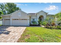 Charming single-story home with a three-car garage, paver driveway, and manicured landscaping at 6130 Japonica Ct, New Port Richey, FL 34655