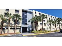 View of the condo building exterior, featuring palm trees and covered entrance at 701 S Madison Ave # 316, Clearwater, FL 33756