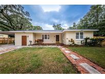 Charming single-story home boasts a lush front lawn, brick pathway, and inviting porch swing at 1205 E Hamilton Ave, Tampa, FL 33604