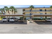 Exterior view of a condo building and parking lot, featuring covered parking and mature landscaping at 14255 Rosemary Ln # 8219, Largo, FL 33774