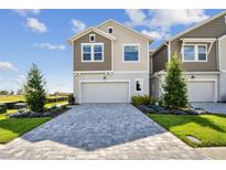 Two-story home featuring a paver driveway, two-car garage, manicured lawn, and neutral color scheme at 10712 Oak Bend Dr, Parrish, FL 34219