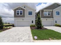 Townhome with a gray and beige facade, two-car garage, modern landscaping, and a brick-paved driveway at 10712 Oak Bend Dr, Parrish, FL 34219