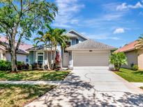 Charming single-Gathering home with well-manicured lawn, palm trees, and a two-car garage on a sunny day at 12327 Glenfield Ave, Tampa, FL 33626