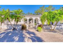 Charming two-story home with lush palm trees, manicured garden beds, and a brick paver driveway at 13483 Heritage Way, Sarasota, FL 34240