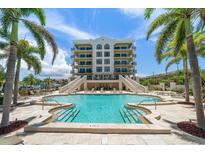 Stunning condo complex featuring a beautiful outdoor pool and lounge area surrounded by lush landscaping at 202 Windward Psge # 304, Clearwater Beach, FL 33767