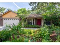 Charming home with mature landscaping, brick accents, and a vibrant red front door at 4215 Water Oaks Ln, Tampa, FL 33618
