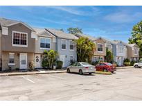 A row of townhomes showcases neat landscaping, reserved parking, and a vibrant blue sky on a sunny day at 6600 121St Ave # 4, Largo, FL 33773