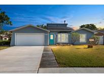 Charming single-story home with a well-manicured lawn, garage and blue door at 7025 Orkney N Ave, St Petersburg, FL 33709