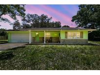 Charming single-story home with a colorful green exterior, stone accents and a welcoming front porch with rocking chairs at 16044 Stur St, Brooksville, FL 34604