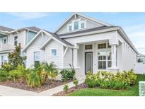 Charming two-story home with a landscaped yard, and covered porch on a sunny day at 28680 Cozy Creek Dr, Wesley Chapel, FL 33543