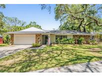 Charming single-story home with a stone accent, well-manicured lawn, and an attached two-car garage at 34 Hickory Ln, Safety Harbor, FL 34695