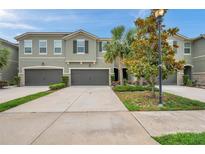 Attractive townhome with a well manicured lawn, beautiful landscaping, and attached two-car garages at 5710 Grand Sonata Ave, Lutz, FL 33558