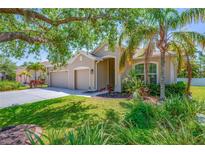 Charming one-story home featuring a spacious driveway, three-car garage, and lush tropical landscaping at 6203 34Th E Ct, Ellenton, FL 34222