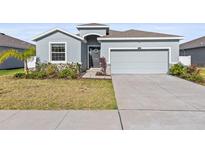 A single Gathering home with a two-car garage, a manicured lawn and stone accents at 7139 Steer Blade Dr, Zephyrhills, FL 33541